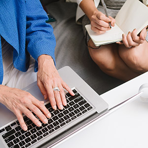 a photo of a hand using a computer and a woman writing for a UX agency in Sydney