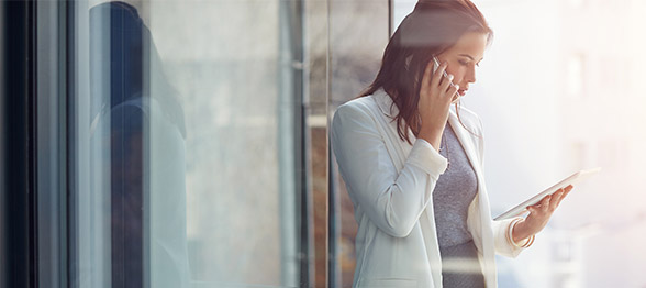 Professional business woman using portable technology devices in office