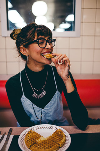 Young lady in a cafe eating a sandwich and smiling