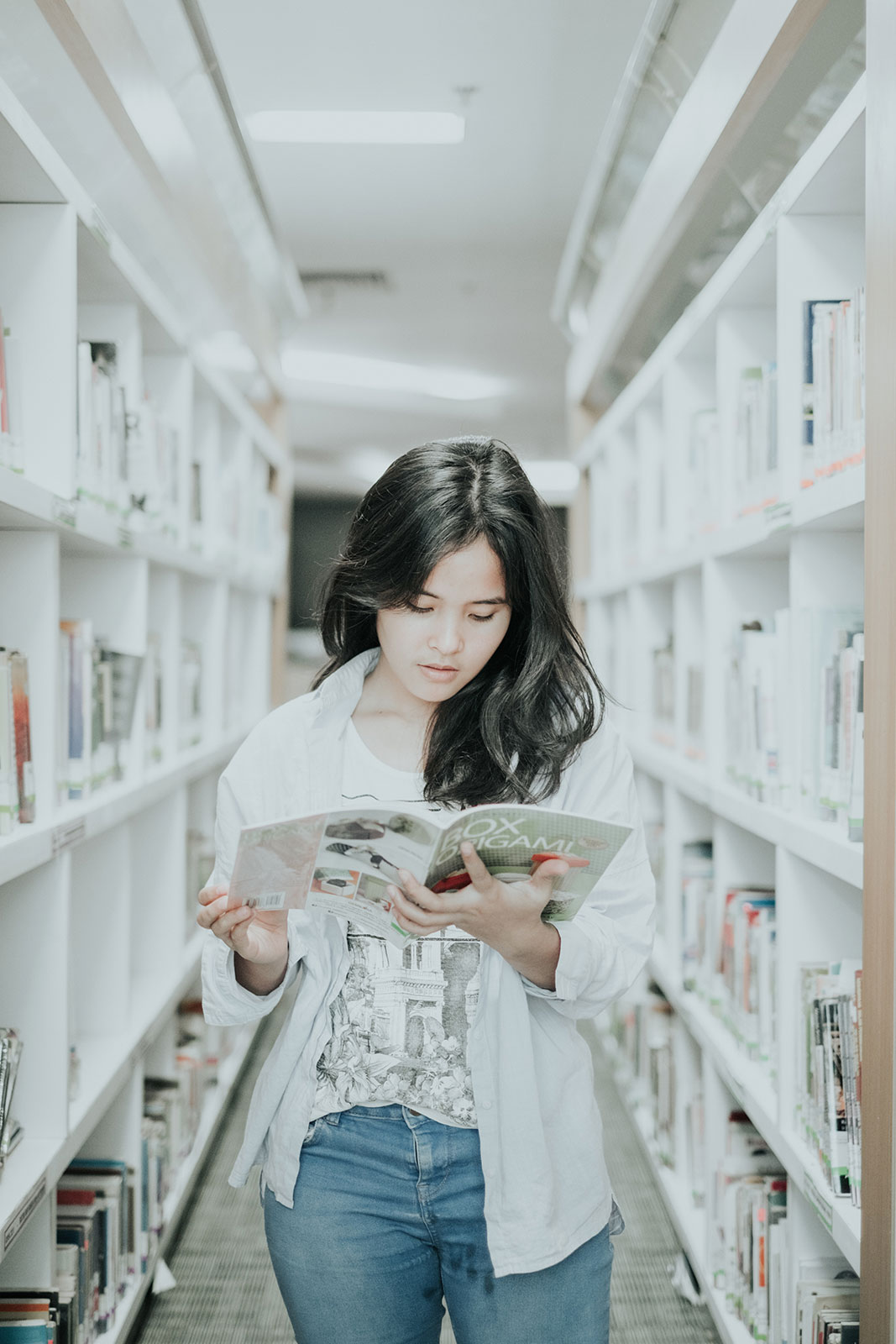 Female student in library reading a book